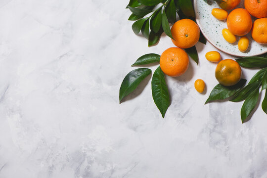 Fresh mandarins with green leaves on marble background. © Olena Bloshchynska