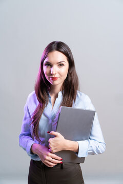 A Young Freelance Business Woman Stands With A Laptop In Her Hands, In Studio With Neon Light.