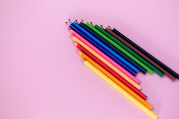 Close-up of colored wooden pencils. Pink background.