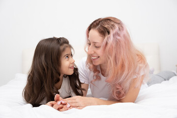 mother play with little active daughter in bed at home, having fun, activity with children