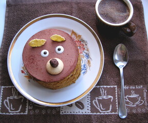 Cupcake in the form of a bear face and a cup of coffee on a towel