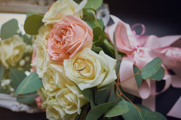 gold rings and a beautiful bridal bouquet of roses on the background. details, wedding traditions. close-up, macro