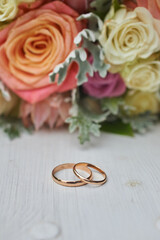 gold rings and a beautiful bridal bouquet of roses on the background. details, wedding traditions. close-up, macro