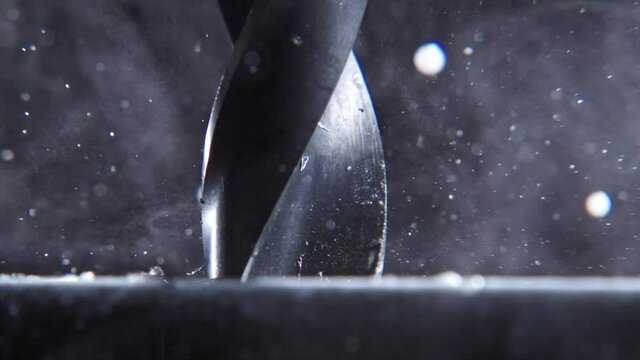 Very close drill drills a sheet metal. Particles are scattered. Slow motion. Very close up drill.