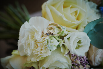gold rings and a beautiful bridal bouquet of roses on the background. details, wedding traditions. close-up, macro