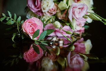 gold rings and a beautiful bridal bouquet of roses on the background. details, wedding traditions. close-up, macro