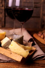 different types of cheeses with wine in glasses on a wooden surface selective focus. cheese platter.