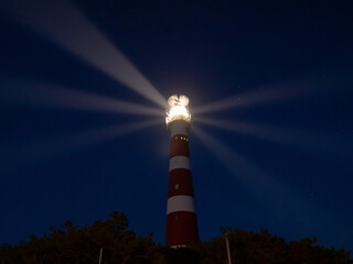 Lighthouse with light rays during night on the island of Ameland, Hollum, Netherlands