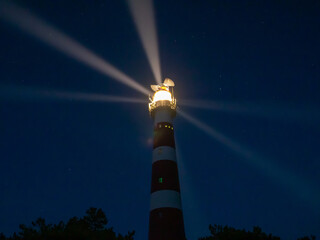 Lighthouse with light rays during night on the island of Ameland, Hollum, Netherlands