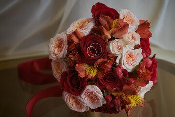 gold rings and a beautiful bridal bouquet of roses on the background. details, wedding traditions. close-up, macro