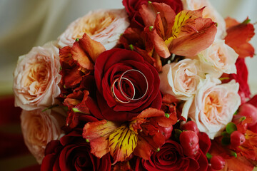 gold rings and a beautiful bridal bouquet of roses on the background. details, wedding traditions. close-up, macro
