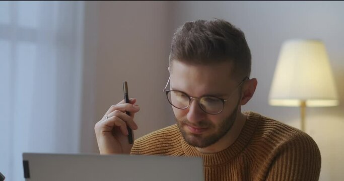 adult male student is listening online webinar or lecture on display of laptop at home, e-learning, portrait
