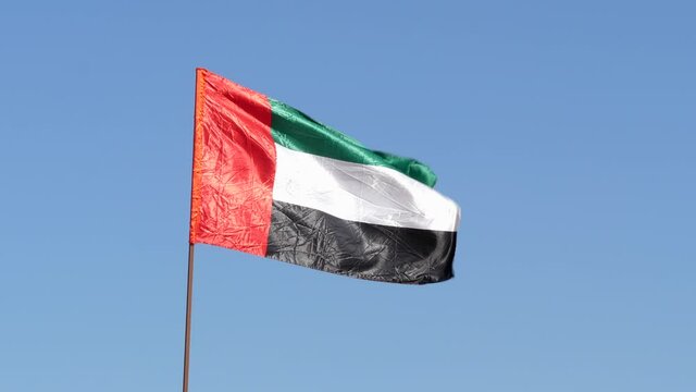 United Arab Emirates flag waving in the wind in front of the blue sky