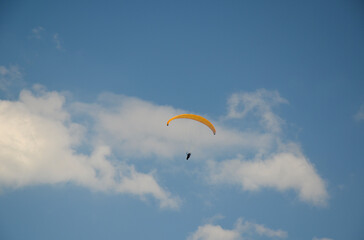 Paraglider flies in the sky over the mountains on a bright sunny day. Paragliding in the sky. Extreme sport.