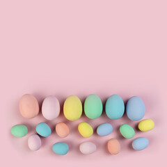 Multicolored Easter eggs and feathers in pastel colors lie on shavings in the form of a frame. Festive Easter card.