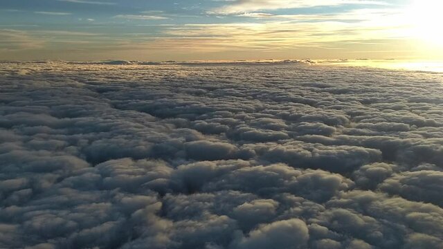 Sunrise over the clouds in central Florida, looking east into the sun. Camera is from a moving jet while panning from left to right.