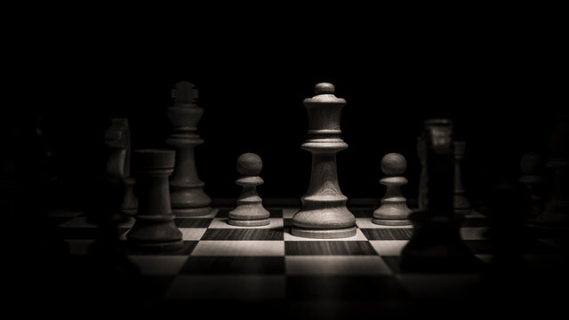 Queen fighting on the chessboard. Low-key concept picture of chess pieces taken in studio and concerning decision making and strategy.