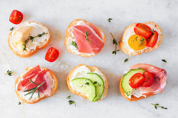 Assortment of cream cheese crostini hors d'oeuvres with a variety of toppings. Above view on a...
