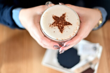coffee in hands decorated with star 