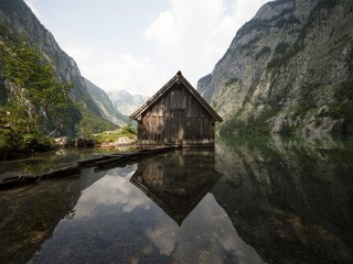 Panorama reflection of wooden boat house shed alpine mountain lake Obersee Fischunkelalm...