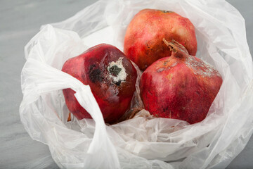 Spoiled pomegranates with mold in disposable plastic bag. Top view. Improper food storage. Concept...