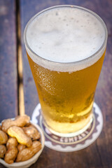 Fresh and cold tap beer pint with peanut on a wooden table