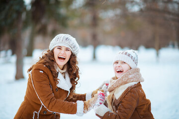 Fototapeta premium smiling mother and child playing outside in city park in winter