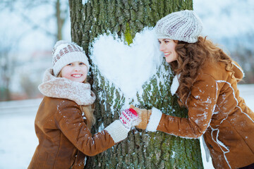 happy stylish mother and child outdoors in city park in winter