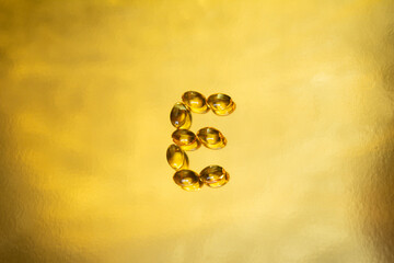 CAPSULAS DE VITAMINA E SOBRE FONDO DORADO