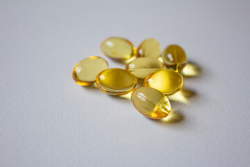CAPSULAS DE VITAMINA E DORADAS SOBRE FONDO BLANCO