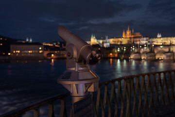 Fototapeta na wymiar city ​​binoculars and railings and in the blurred background Charles Bridge and Prague Castle in the center of Prague in Podvece