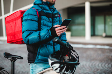   Man courier using a map app on mobile phone to find the delivery address in the city.