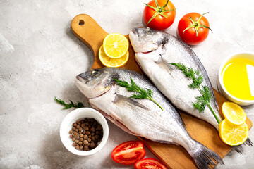 Raw dorado fish on a cutting board on a concrete background with ingredients for cooking. Top view...