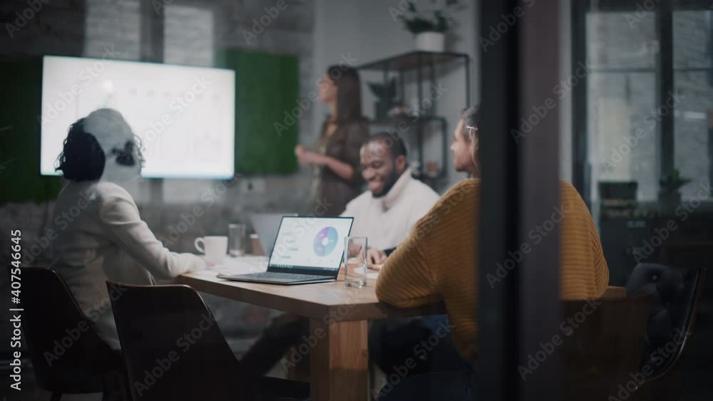 Poster project manager makes a presentation for a young diverse creative team in meeting room in an agency.