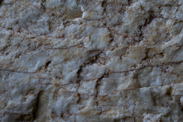 Textura de una roca en tonos grises, beige y marron. 