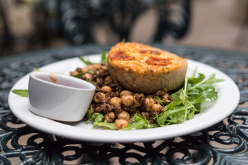 Delicious vegetarian quiche served with fresh salad and chickpeas at the Victoria Yum bakery (Doughty Street, London, UK). Beautiful art nouveau table. Charles Dickens Museum garden cafe.