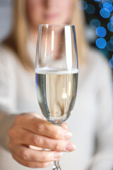 a girl in a white sweater holds a glass of sparkling wine on her outstretched hand