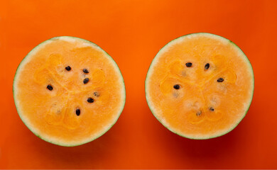 half of fresh ripe orange watermelon  around orange background. concept shot