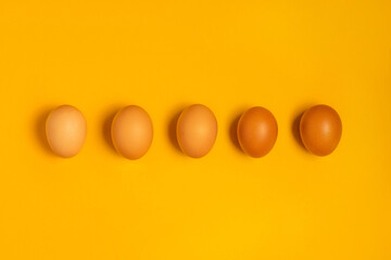 Brown chicken easter eggs on yellow background. Happy Easter concept. Top view, flat lay with copy space