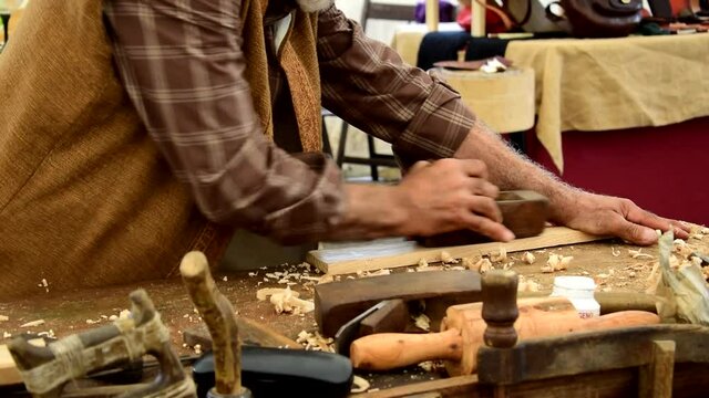 Carpenter sanding wood with a planer at a craft fair in Galicia, Spain