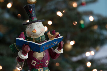 Christmas wooden snowman figure with bokeh Christmas tree lights in the background, an American...