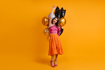 Full-length portrait of appealing birthday girl. Inspired woman in long skirt holding party balloons.