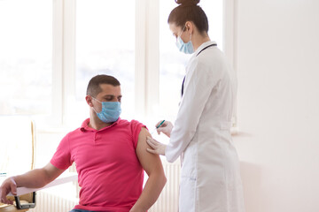 Obraz premium Young Female doctor in protective mask injecting or prepairing for injecting vaccine against coronavirus or ncov 19 or covid into patient's arm