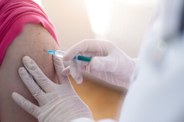 Young Female doctor in protective mask injecting or prepairing for injecting vaccine against coronavirus or ncov 19 or covid into patient's arm