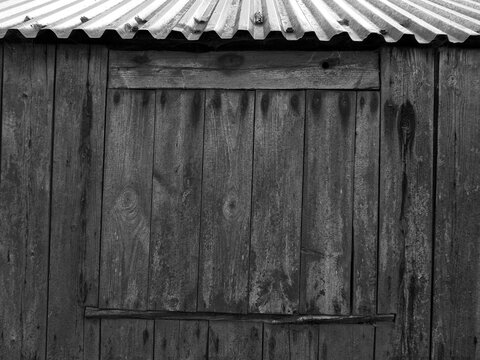 blocked up window with weathered planks on a rustic shed or farmhouse outbuilding with a tine roof