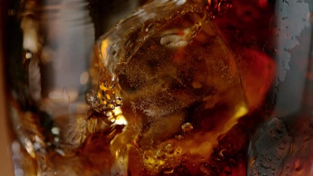 Camera Follows Ice Cubes Falling into Cola, Macro Shot. Super Slow Motion Filmed on High Speed Camera.