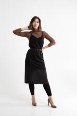 Fototapeta premium Full length portrait of brunette girl in black and brown clothes on high heels isolated on white studio background. Vertical view 