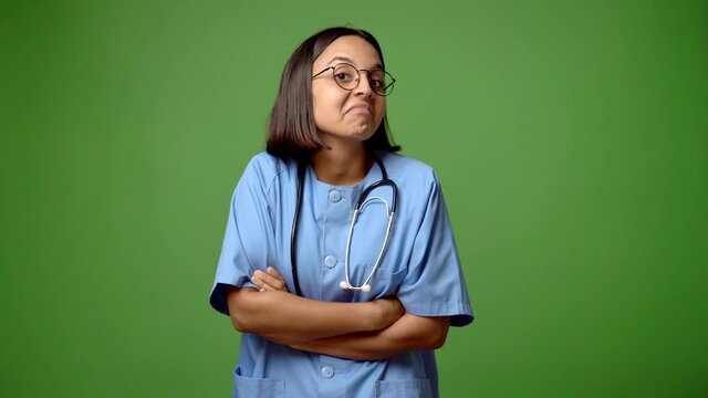 Woman with nurse uniform making unimportant and doubts gesture while lifting the shoulders and the palms of the hands