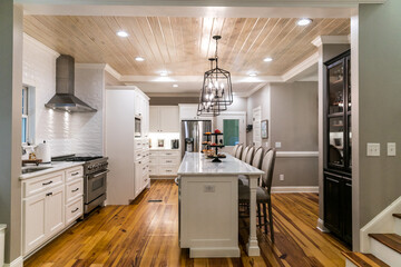 Large renovated white kitchen with textured subway tile, black iron lights and pine hardwood...