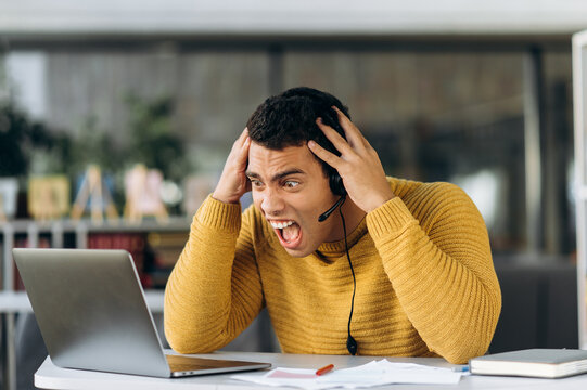 Screaming Businessman Sits At The Work Desk. Hispanic Male Freelancer Accidentally Deleted Important Document. Shocked Employee Have A Problem With Internet Connection While Working Online